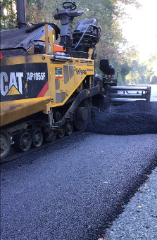 A road paver vehicle places recycled asphalt modifier onto a road in Ridley Creek State Park.