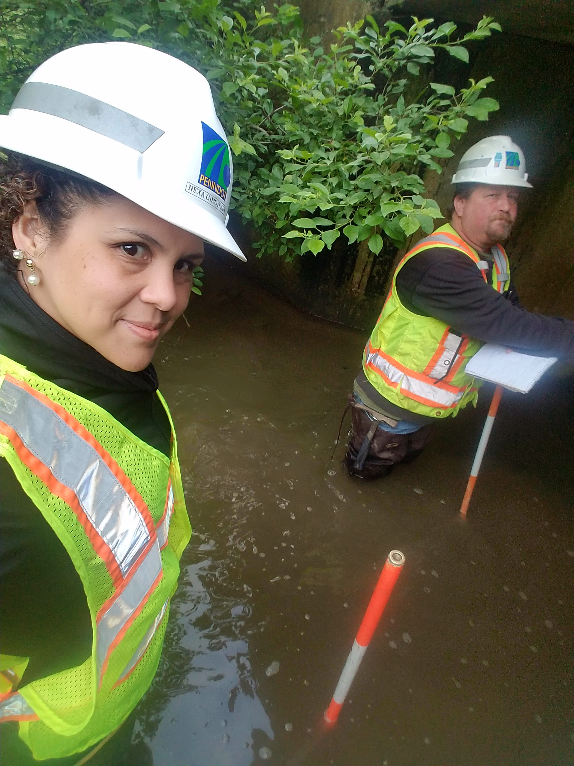 Nexa Castro with a hard hat and construction vest on taking a selfie on a worksite.