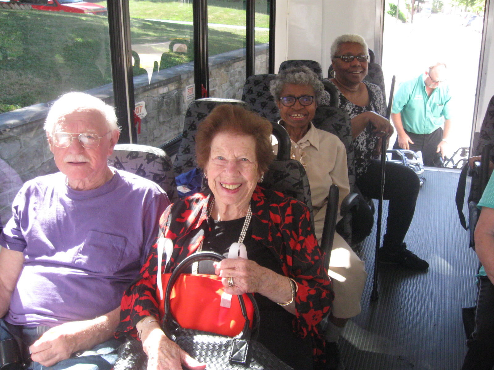 Three women and one man sit smiling in a bus.