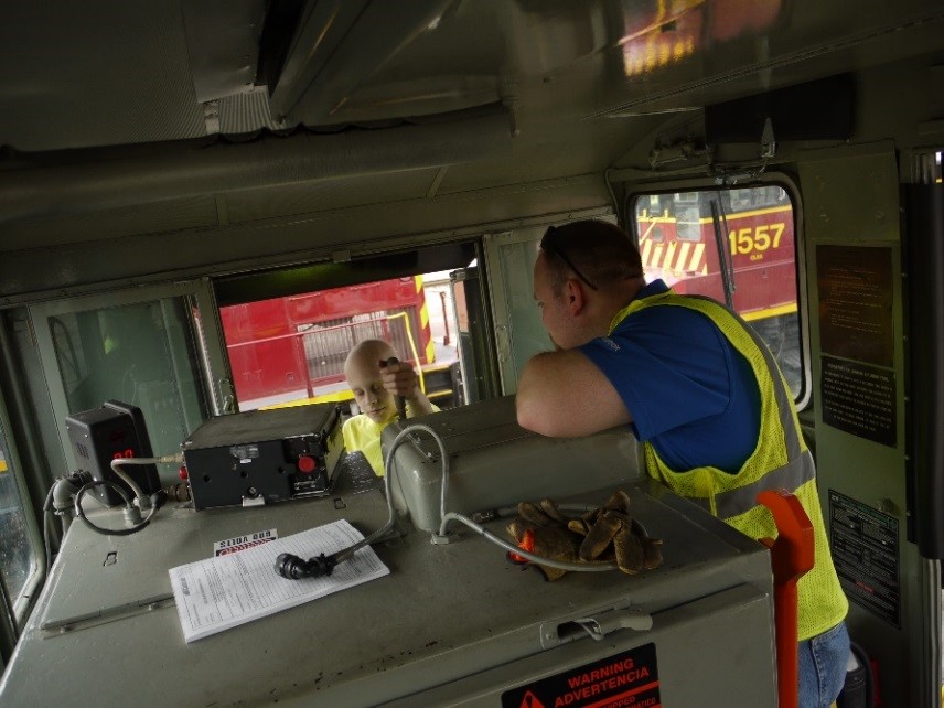 Nine-year-old Parker pulls a lever inside the cabin of a locomotive with Brian Wingrove looking on.