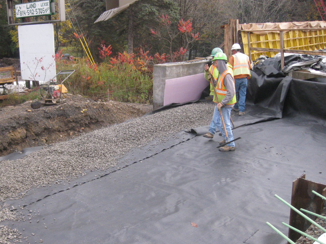 Construction workers spreading gravel over a tarp.
